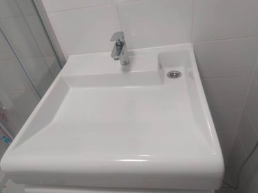 Установлена новая белоснежная раковина с блестящим смесителем и аккуратным сливом. Завершена работа по монтажу, обеспечена герметичность и функциональность.