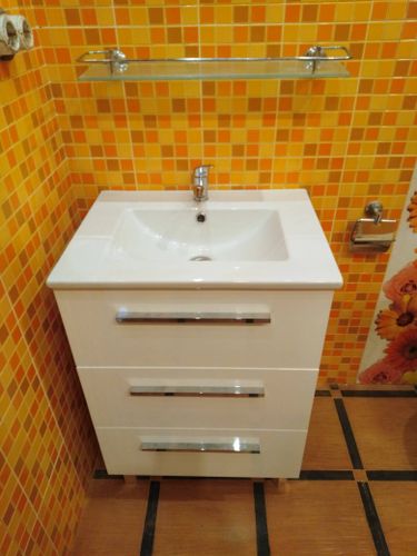 Установлена раковина с тумбой, подключен смеситель, закреплены трубы, проверена герметичность соединений, добавлена полка, организовано пространство для хранения.