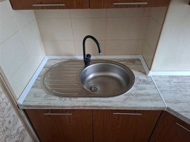 Установлена столешница из ДСП, вырезано отверстие для мойки, закреплены панели, подогнаны края, герметизированы стыки, подключен смеситель, произведена проверка устойчивости конструкции.