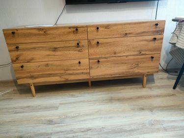 Собран деревянный комод: установлены ящики, прикреплены ручки, закреплены ножки, проверена устойчивость, выровнены детали, обеспечена функциональность, завершена сборка.