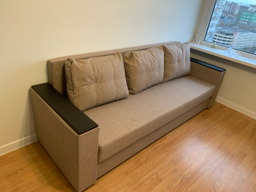 Собран диван: установлены подлокотники, закреплены спинка и сиденье, добавлены подушки. Проверена устойчивость конструкции, завершена установка в комнате.