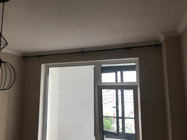 Закреплен металлический карниз над окном. Установлены крепления, обеспечивающие надежность конструкции. Карниз ровно выровнен, готов для использования с занавесками.