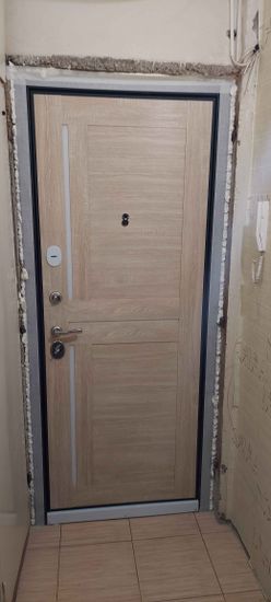Установлена новая пластиковая дверь, закреплена в проеме, зазоры заполнены монтажной пеной, обеспечена герметичность и шумоизоляция. Установлены ручки и замки, проверена функциональность.
