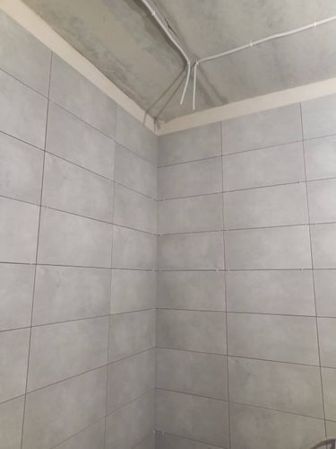 На стенах ровно уложены керамические плитки серого оттенка, швы аккуратно выровнены, поверхность тщательно подготовлена, соблюдена симметрия, завершён эстетичный монтаж.