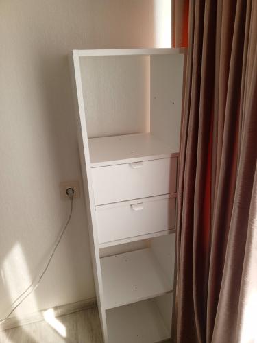 Собран белый стеллаж с двумя ящиками и полками. Установлены все элементы, обеспечена устойчивость и функциональность. Работа завершена, конструкция готова к использованию.