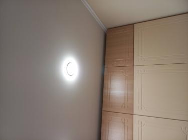 На потолке закреплён светильник, подключённый к электросети. Проведены работы по монтажу, обеспечена надёжная фиксация и корректное функционирование освещения в помещении.