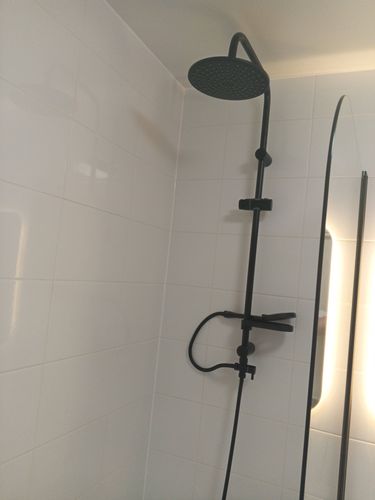 Изображение демонстрирует завершённую установку электрического полотенцесушителя: подключение к электросети, монтаж на стену, проверка исправности, соблюдение техники безопасности.