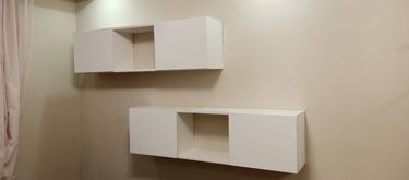 На стене закреплены две белые полки с нишами. Конструкция надежно установлена, выровнена по уровню, обеспечивает функциональность и эстетичный вид в интерьере.