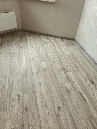 На ровное основание уложено покрытие, тщательно подогнаны стыки, выполнена обрезка по периметру, установлены плинтусы, поверхность гладкая и аккуратная.