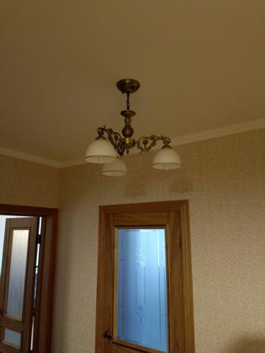 Люстра надежно закреплена на потолке, подключена к электросети, обеспечивая равномерное освещение комнаты. Установлены все необходимые крепления, проверена безопасность конструкции.