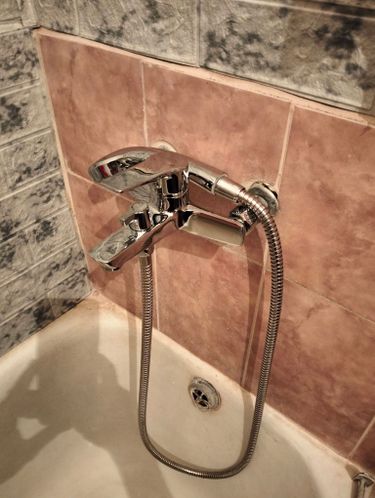 Установлен новый блестящий кран в ванной, подключен гибкий шланг, проверена герметичность соединений, обновлён внешний вид плитки вокруг.