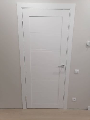 Установлена деревянная дверь с одной створкой. Врезаны петли, закреплён замок, смонтирована ручка. Коробка выровнена, наличники установлены, конструкция отрегулирована для плавного закрывания.