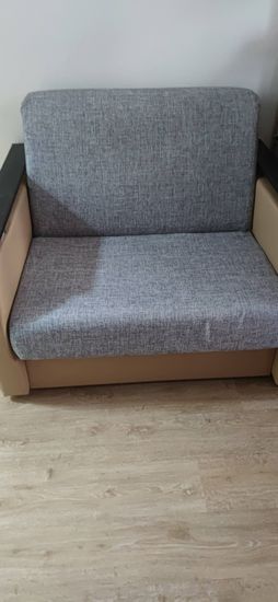 Собран диван: установлены каркас, подлокотники, спинка и сиденье. Все элементы соединены, обивка натянута, конструкция устойчива, готова к использованию.