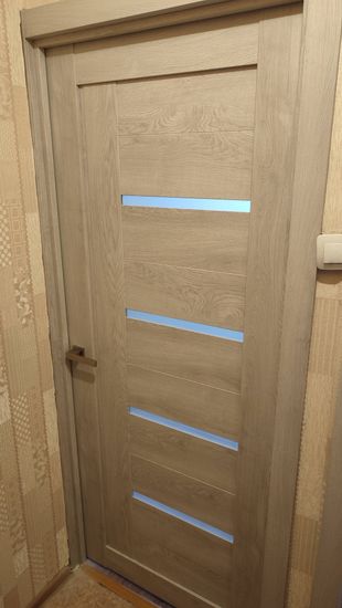 Установлена новая одностворчатая дверь с фурнитурой, выполнена подгонка полотна, закреплены петли, врезан замок, отрегулировано прилегание, оформлен проем наличниками.