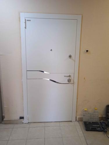 Установлена новая белая дверь с современным дизайном и надежными замками. Обновлённый дверной проём аккуратно оформлен, обеспечивая безопасность и эстетичный вид.