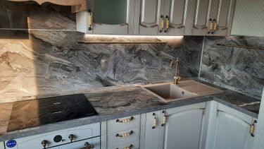 Изготовлена и установлена кухонная поверхность с вырезами под варочную панель и мойку, выполнена подгонка под размеры помещения, обеспечена точность стыков и гладкость краев.