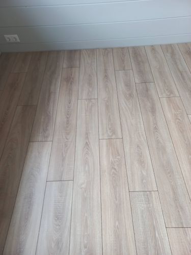 Уложено новое покрытие, ровные панели светлого оттенка, без зазоров. Пол полностью обновлён, создаёт уютную атмосферу в помещении.