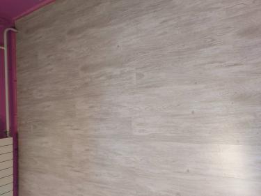 На ровное основание уложено покрытие светлого оттенка. Полы выглядят аккуратно, без зазоров и дефектов, создавая гладкую и эстетичную поверхность в помещении.