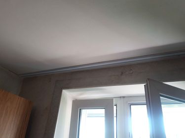 На стене закреплен карниз, ровно установленный над окном. Все крепления надежно зафиксированы, конструкция выглядит устойчиво и аккуратно. Завершенная работа демонстрирует качество монтажа.