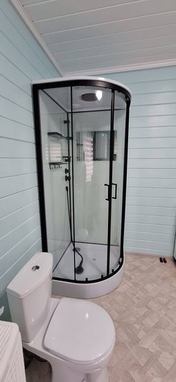 Установлена современная душевая конструкция с прозрачными стенками и черной фурнитурой. Проведены работы по подключению водоснабжения и герметизации швов. Обновлен интерьер помещения.