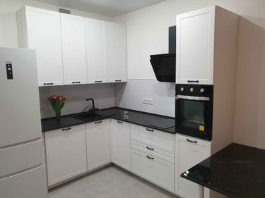 На кухне установлен новый черный столешничный материал, точно подогнанный под размеры шкафов и техники. Все элементы аккуратно соединены, обеспечивая гладкую поверхность.