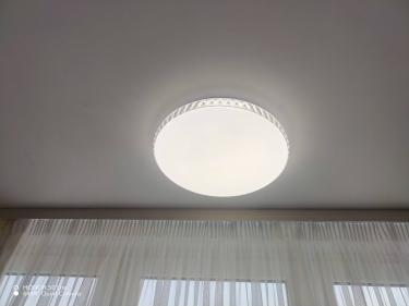 На потолке закреплён новый светильник, подключённый к электросети. Провода аккуратно спрятаны, устройство ровно установлено, обеспечивает равномерное освещение. Завершено безупречно.
