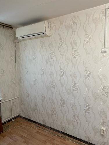 На стенах аккуратно размещены обои с изящным узором, создающим гармоничный интерьер. Поверхность ровная, без видимых швов и дефектов, что придаёт помещению завершённый вид.