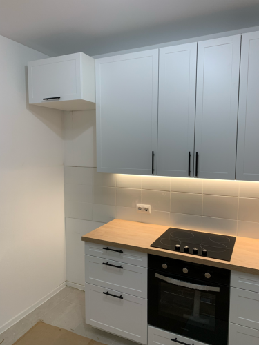 Установлены шкафы, закреплены фасады, смонтирована столешница, подключена варочная панель, выполнена подсветка. Все элементы надежно зафиксированы, обеспечивая функциональность и эстетичность.