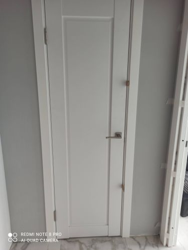 Установлена белая одностворчатая дверь с ручкой и петлями, выполнена регулировка, монтаж коробки, проверка функциональности. Завершено оформление проема, обеспечена надежная фиксация.