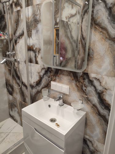 Зеркало аккуратно закреплено на стене ванной комнаты, выровнено по уровню. Использованы крепежные элементы, обеспечивающие надежность и безопасность установки. Работа завершена.