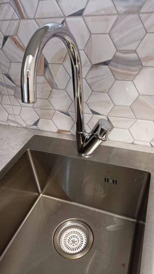 Установлен новый блестящий кран на кухонную раковину, подключены водопроводные трубы, проверена герметичность соединений, обеспечена исправная работа, устранены протечки, завершена настройка.