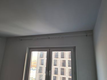 Установлен потолочный карниз для штор над окном. Закреплены кронштейны, обеспечена надежная фиксация конструкции. Работа завершена, готово к использованию.