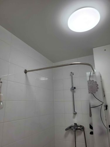 Закреплена изогнутая штанга для шторы в ванной. Надежно установлена на стенах, обеспечивая устойчивость и функциональность. Завершено аккуратно, с учетом эстетики и удобства использования.