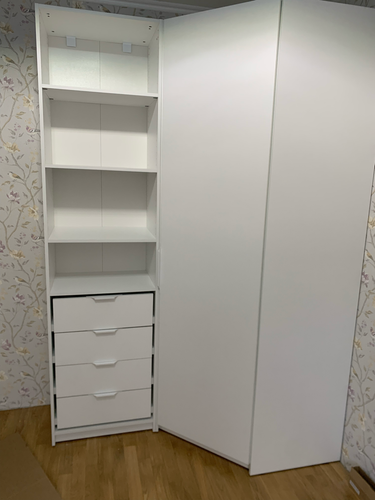 Установлена белая полка в углу комнаты, закреплена на стене. Полка состоит из нескольких секций, обеспечивая дополнительное место для хранения. Работа выполнена аккуратно и надежно.