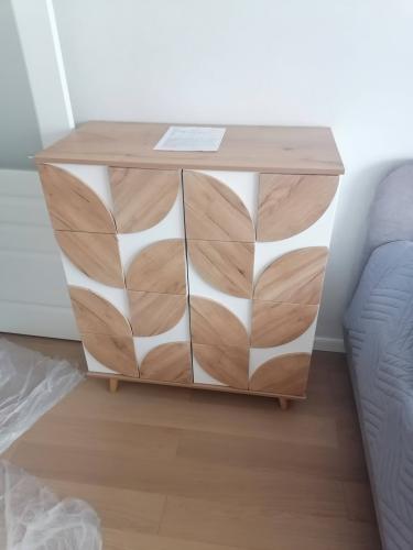 Собрана мебель с деревянными фасадами и ножками. Установлены дверцы, закреплены элементы, проверена устойчивость. Готовое изделие стоит на полу рядом с диваном.