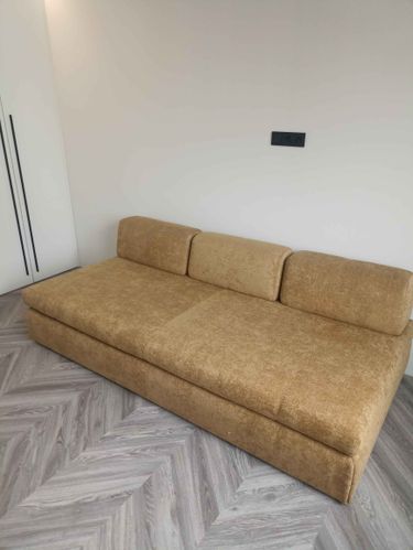 Собран диван: установлены каркас, подлокотники, спинка, сиденье. Все элементы надежно закреплены, обивка натянута. Проверена устойчивость, функциональность. Готов к использованию.