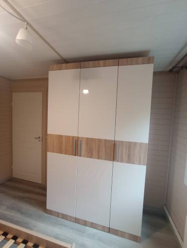 Собран вместительный шкаф с тремя дверцами, выполненный в сочетании светлых и древесных оттенков. Установлены ручки, обеспечивающие удобное открытие. Работа завершена аккуратно.