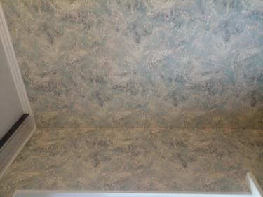 На стенах аккуратно закреплён стеклохолст с абстрактным узором, создающим текстурный эффект. Поверхность ровная, без видимых швов, придаёт комнате стильный вид.