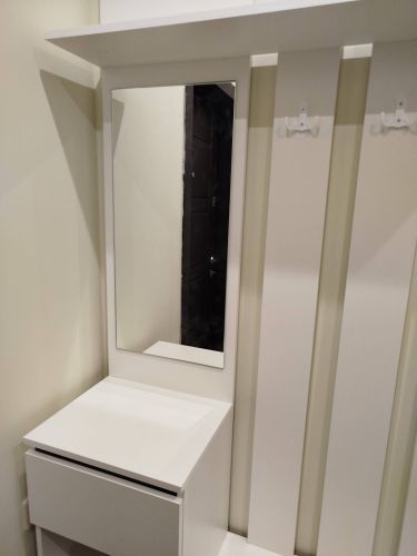 Установлены крючки, закреплено зеркало, собран шкаф с полкой и ящиком. Все элементы надежно зафиксированы, обеспечивая функциональность и эстетичный вид.