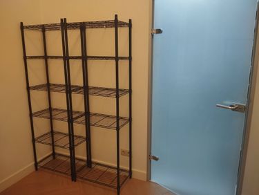 Собрана металлическая конструкция с полками, установленная в углу комнаты. Все элементы надежно закреплены, обеспечивая устойчивость и функциональность для хранения различных предметов.