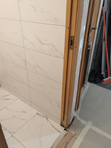 На полу и стенах уложена керамика с мраморным узором. Швы аккуратно затерты, поверхность ровная, без дефектов. Углы и стыки обработаны, обеспечивая целостность покрытия.