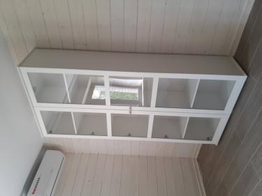 Собран шкаф с полками и стеклянными дверцами, установлен на ровный пол. Все детали надежно закреплены, дверцы ровно висят, обеспечивая плавное открытие.