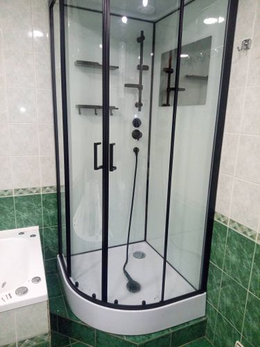 Установлена современная душевая кабина с прозрачными дверцами, черными рамами и полочками. Проведены работы по подключению сантехники и герметизации стыков. Обновлен интерьер ванной комнаты.