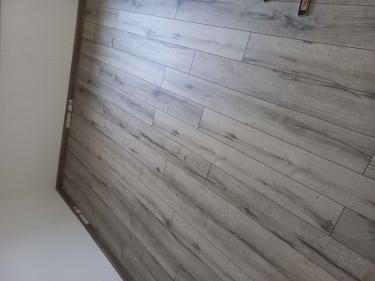 Завершена укладка напольного покрытия: панели аккуратно размещены на ровной поверхности, стыки плотно соединены, установлены плинтусы, обеспечивая завершенный вид и долговечность.