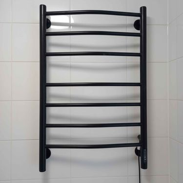 На стене закреплён электрический прибор для сушки полотенец, подключённый к сети. Устройство установлено ровно, провода аккуратно спрятаны, обеспечена надёжная фиксация.