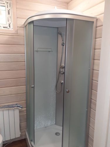 Установлена современная душевая кабина с прозрачными стенками и металлическими элементами. Завершено подключение водоснабжения и герметизация стыков, обеспечена функциональность.