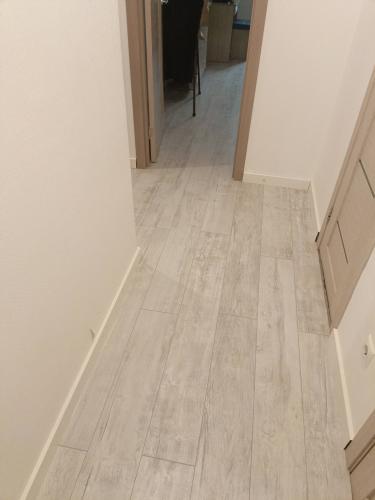 Уложено напольное покрытие из ламината на подготовленное основание в коридоре. Пол ровный, без зазоров, с аккуратными стыками и плинтусами. Светлый оттенок придаёт помещению уют.