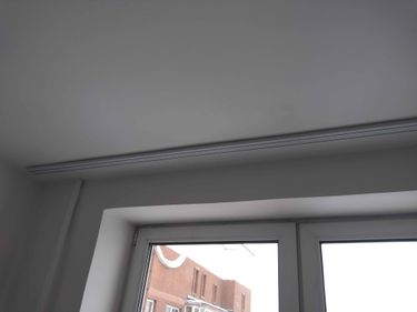 Закреплен профиль над окном, обеспечивающий надежное крепление для штор. Установлен ровно, без видимых дефектов, с учетом всех необходимых параметров для функциональности и эстетики.