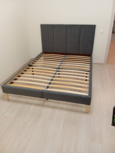 Собрана двуспальная кровать: каркас установлен, ламели закреплены, изголовье прикреплено. Все элементы соединены, конструкция устойчивая, готова к использованию.