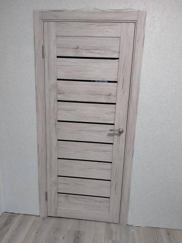 Установлена новая деревянная дверь, закреплены петли, врезана ручка, выровнена коробка, зафиксированы наличники, проверена плавность открывания и закрывания, обеспечена звукоизоляция.